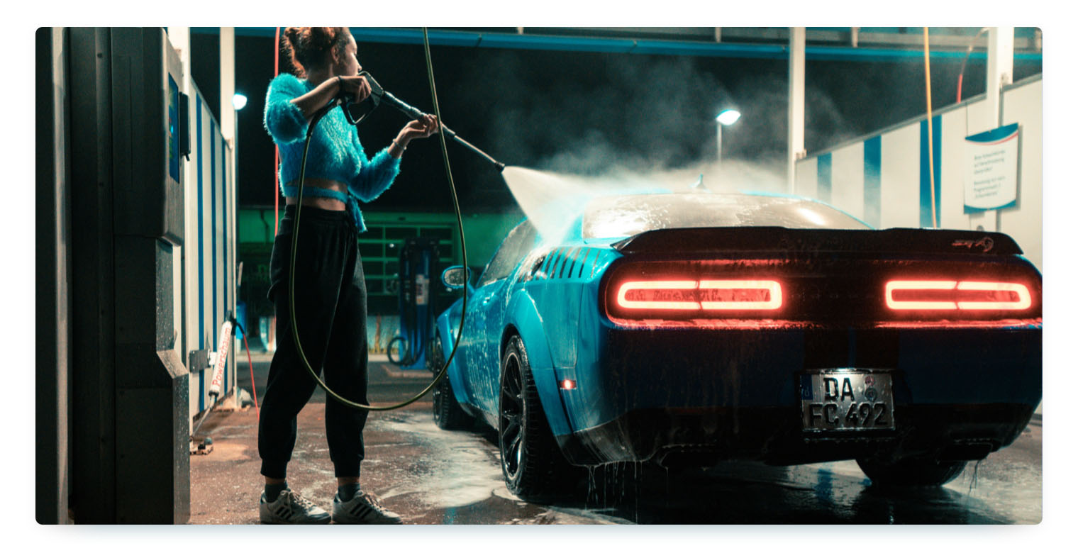 A woman hoses down an oldtimer car in a garage