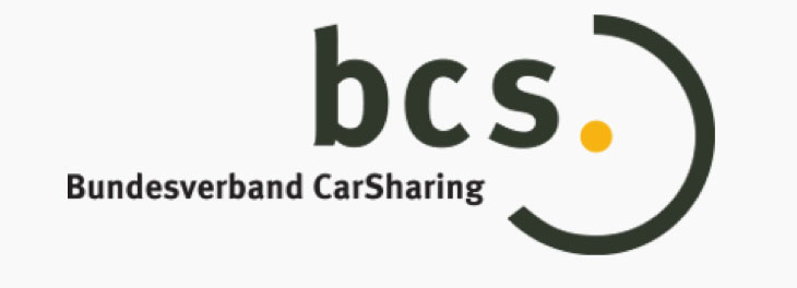 The logo for the German car-sharing association, "Bundesverband CarSharing," which is abbreviated as "bcs." The letters "bcs" are in a dark green font, and the "c" and "s" are enclosed within a partial circle. A single yellow dot sits in the middle of the partial circle.