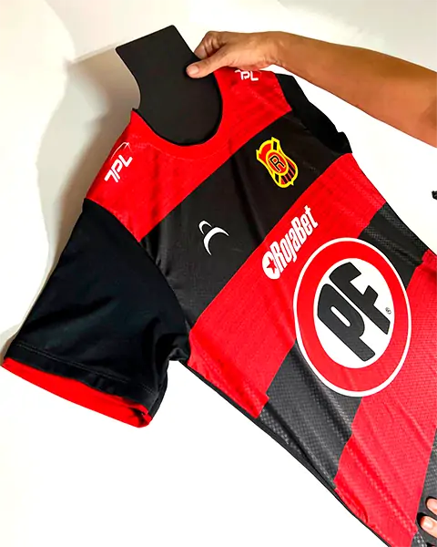 Camiseta de fútbol rojo y negro de Deportes Melipilla con logos de sponsor y 7PL en la manga.