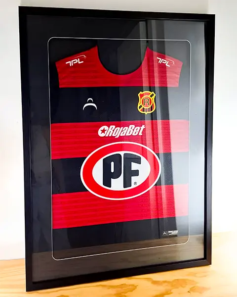 Camiseta roja y negra del equipo de fútbol de Rangers enmarcada sobre una superficie de madera.