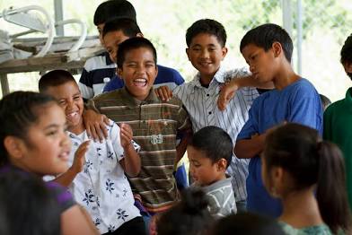 Image of kids laughing as they are gathered in a circle.