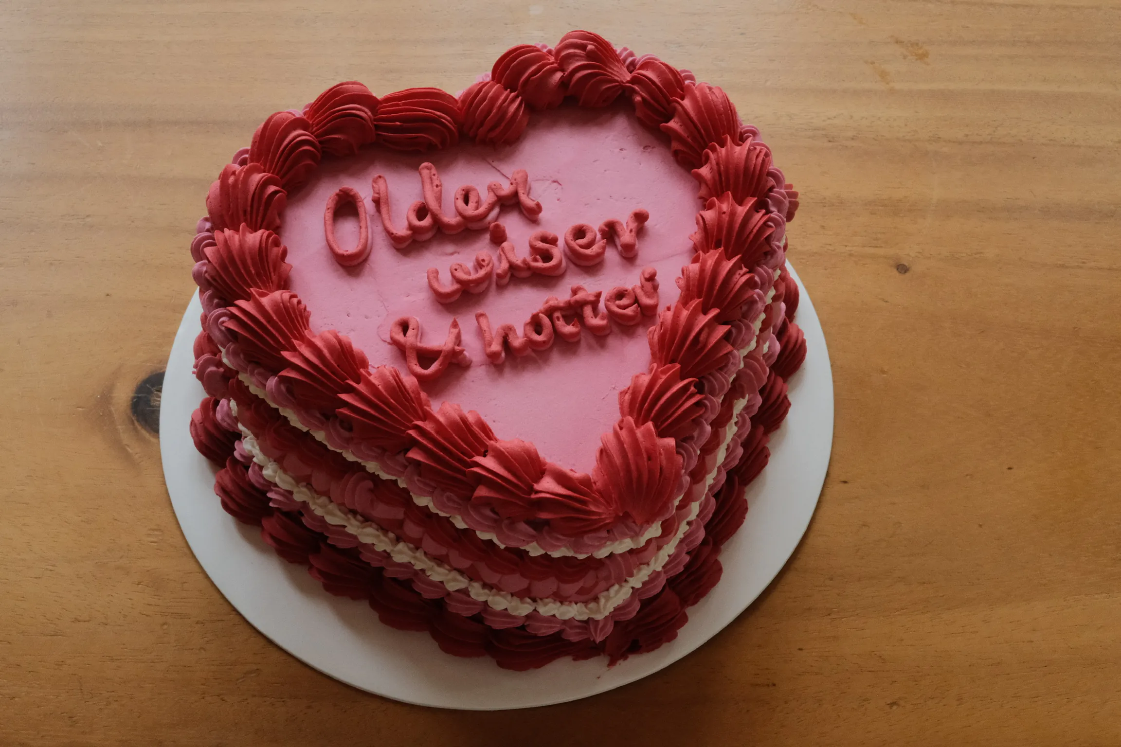 Heart shaped birthday cake with the phrase "older, hotter, wiser"