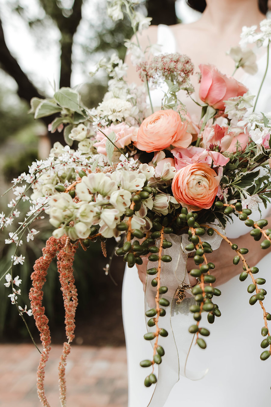 A bride holding a bouquet of succulents, peonies and atypical florals.