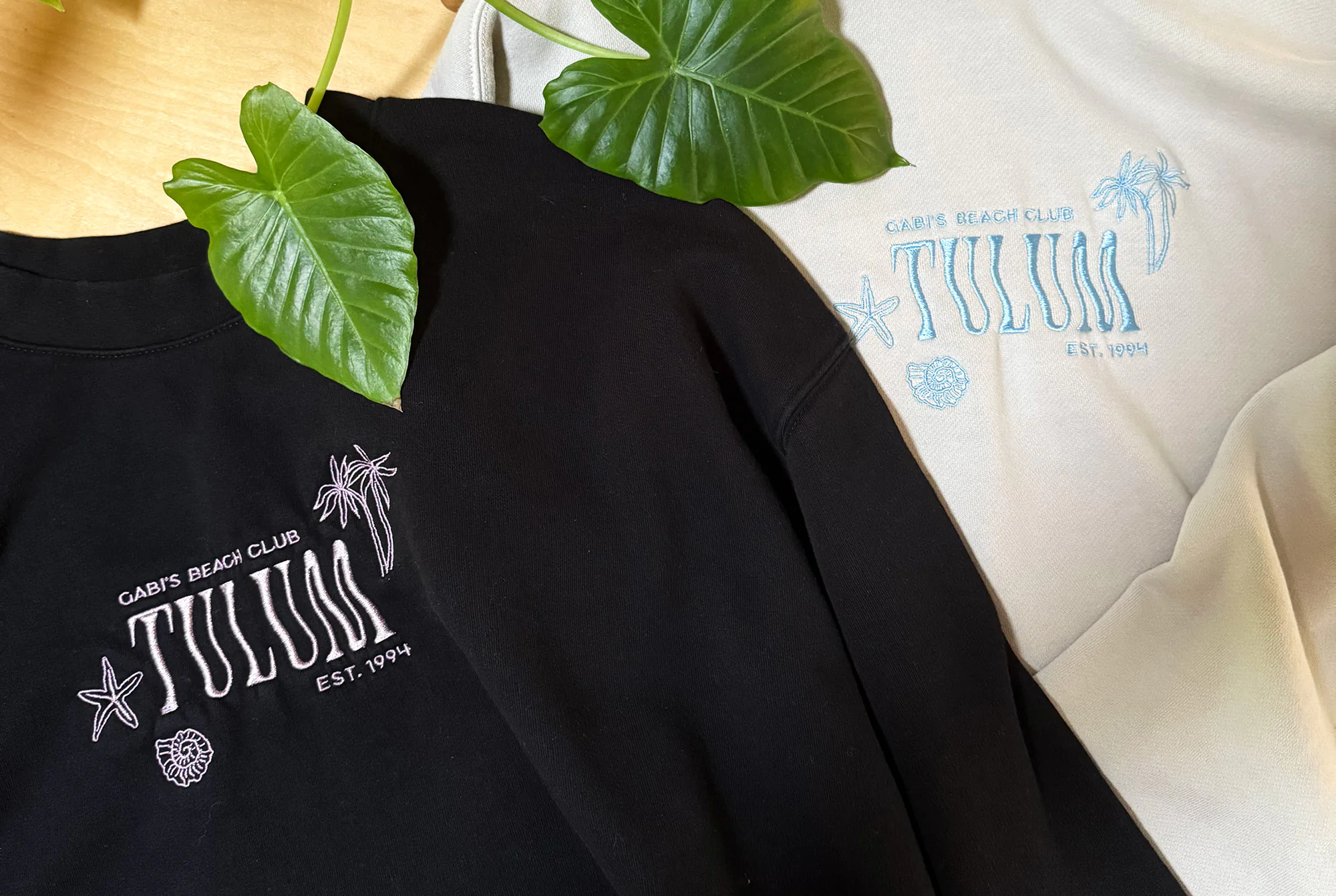 Two sweatshirts laid out on a table with Gabi's Beach Club Tulum embroidered on the front.