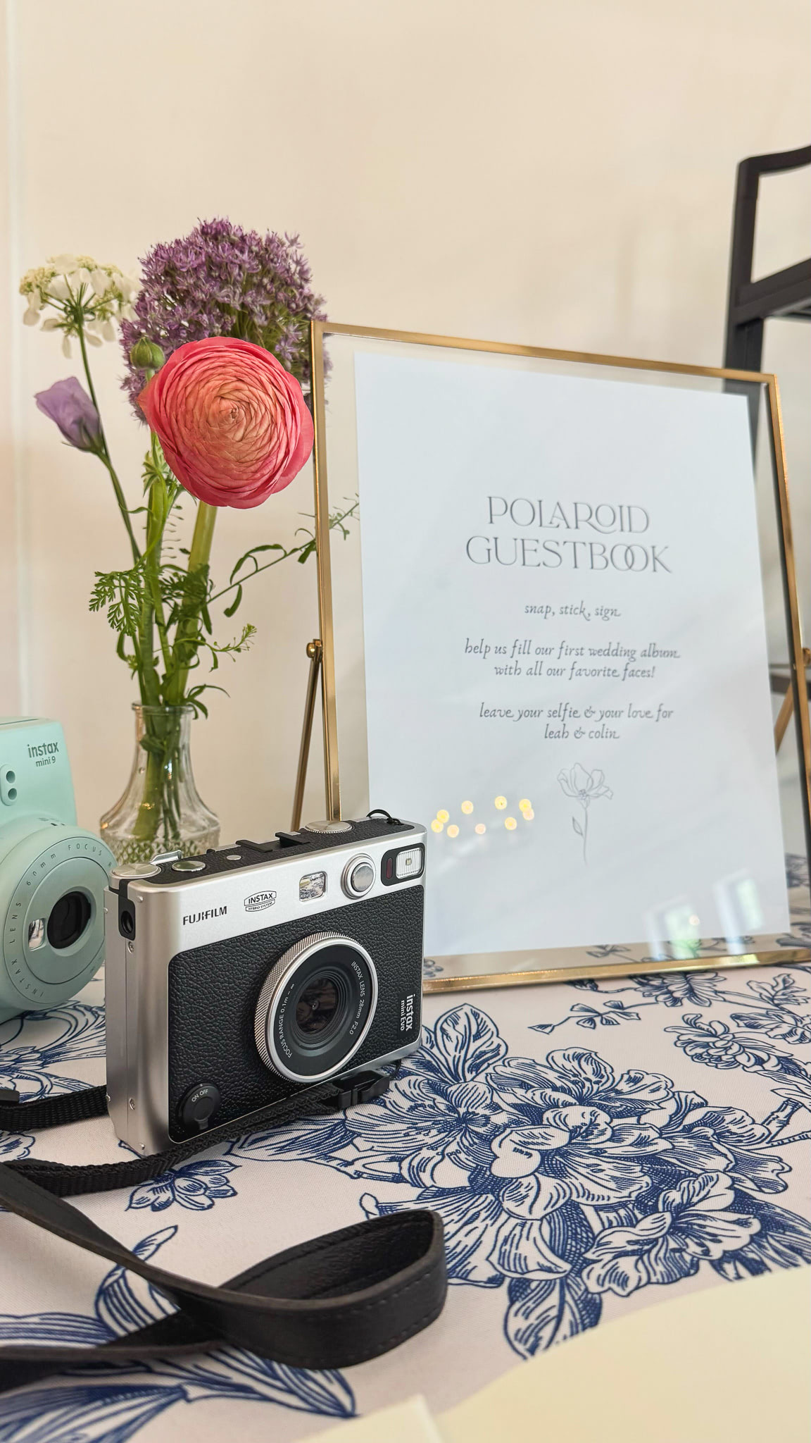 A camera sits on a table next to a sign with instructions for a polaroid guestbook