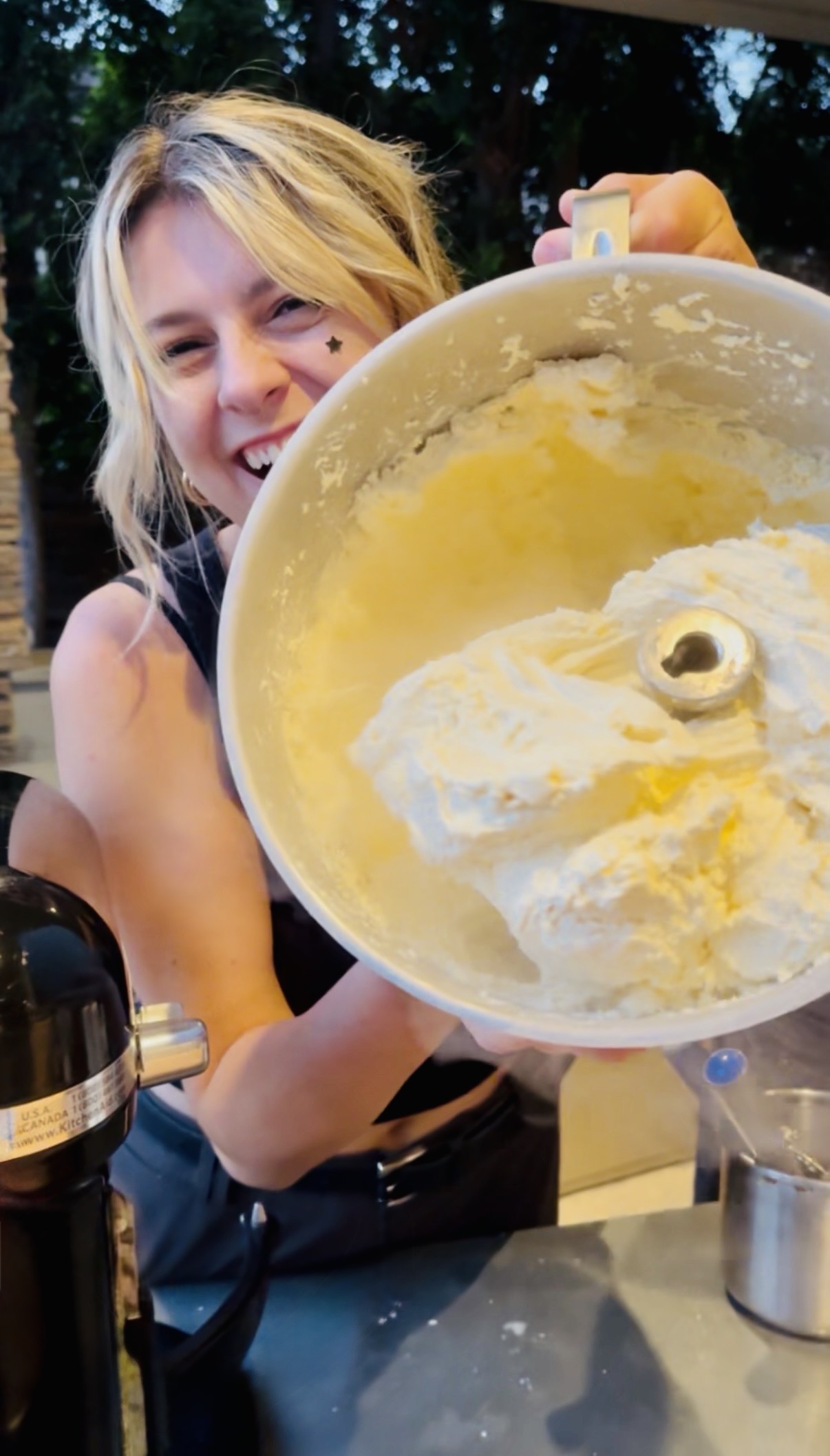 A smiling woman holds up a container of freshly whipped ice cream