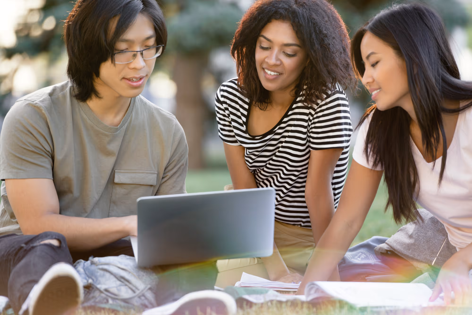 Group of international students studying together with a laptop in a public park