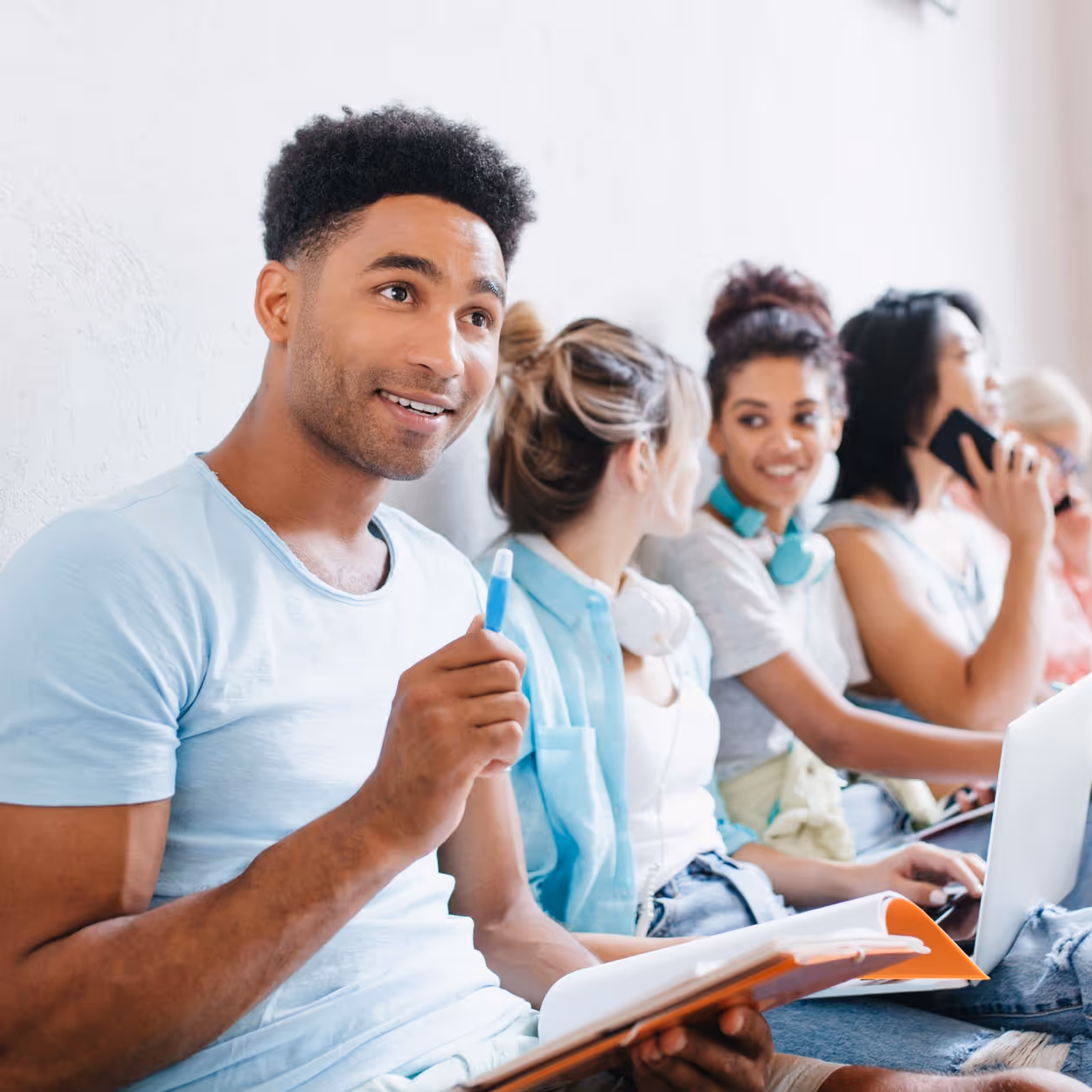 Group of international students sitting against a wall, chatting and studying