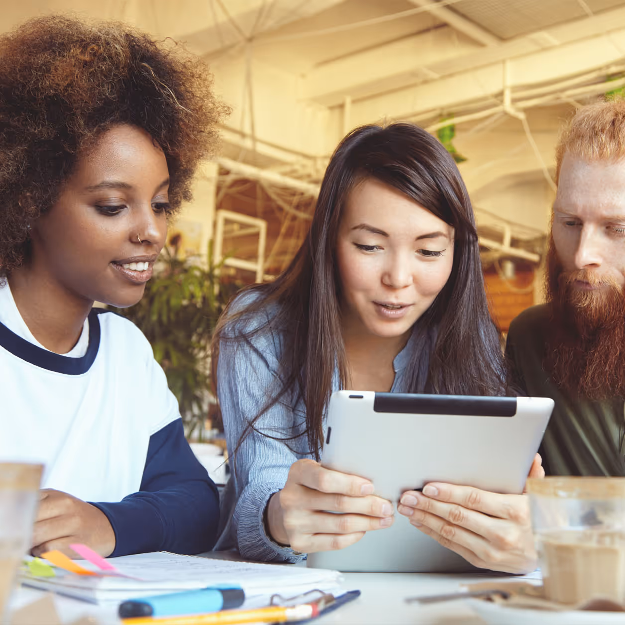 Students looking at a tablet while working together at a desk