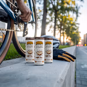 Three Perico Espresso Martini energy drinks next to a cyclist, gloves, and helmet—ideal clean caffeine fuel for endurance and high performance.