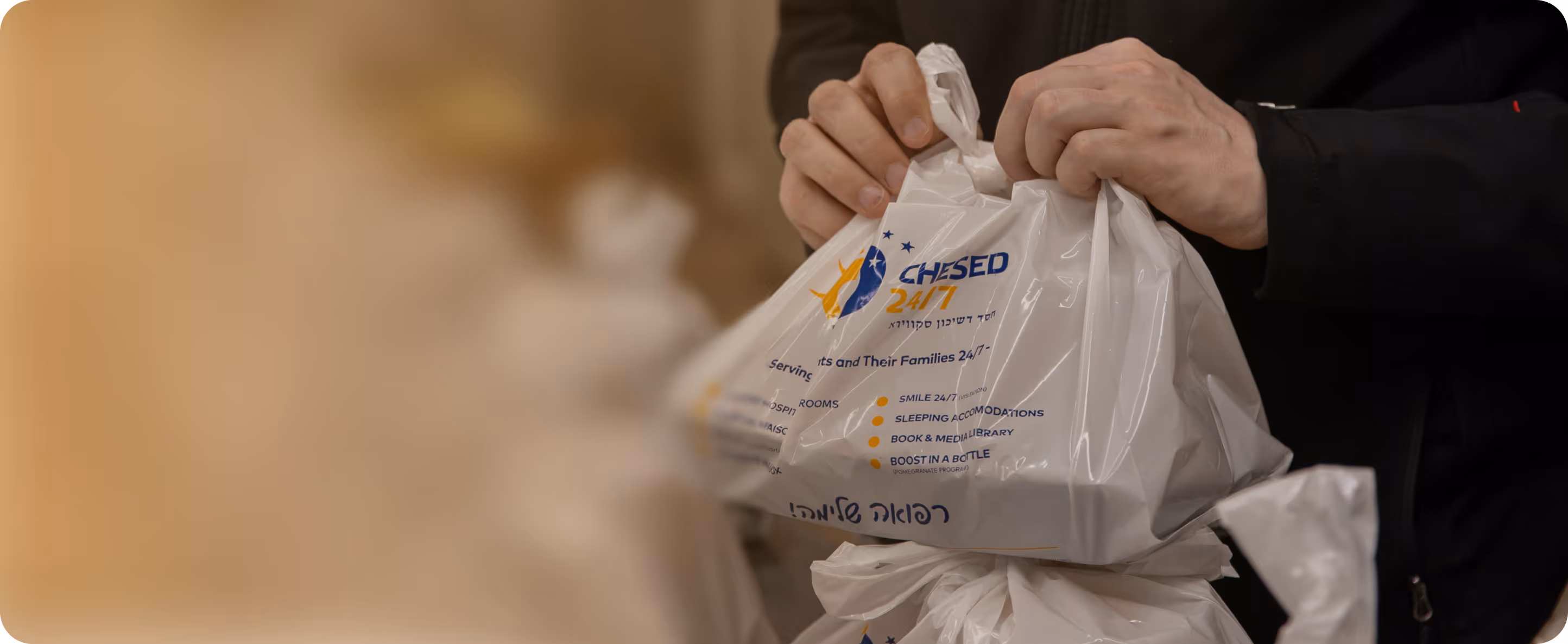 Person tying a plastic bag labeled 'Chesed 24/7' featuring services like smile 24/7, sleeping accommodations, book & media library, and Boost in a Bottle.