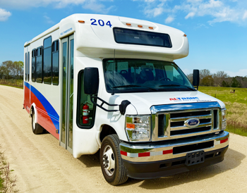 ALTRANS Bus parked in rural setting, cows, field, dirt road mid day