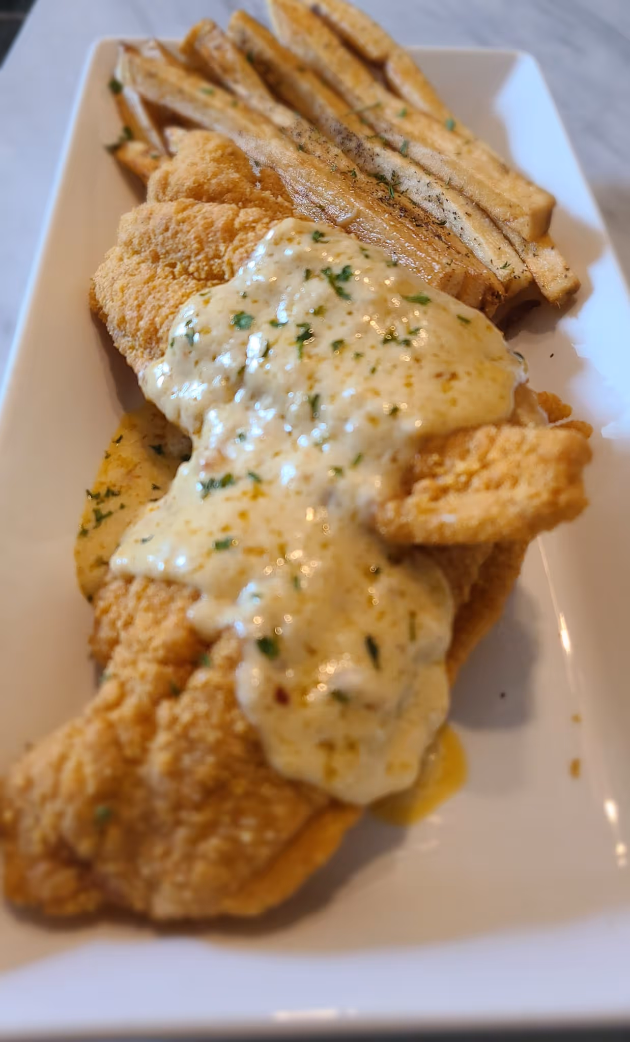 A plate of fish with a white sauce.