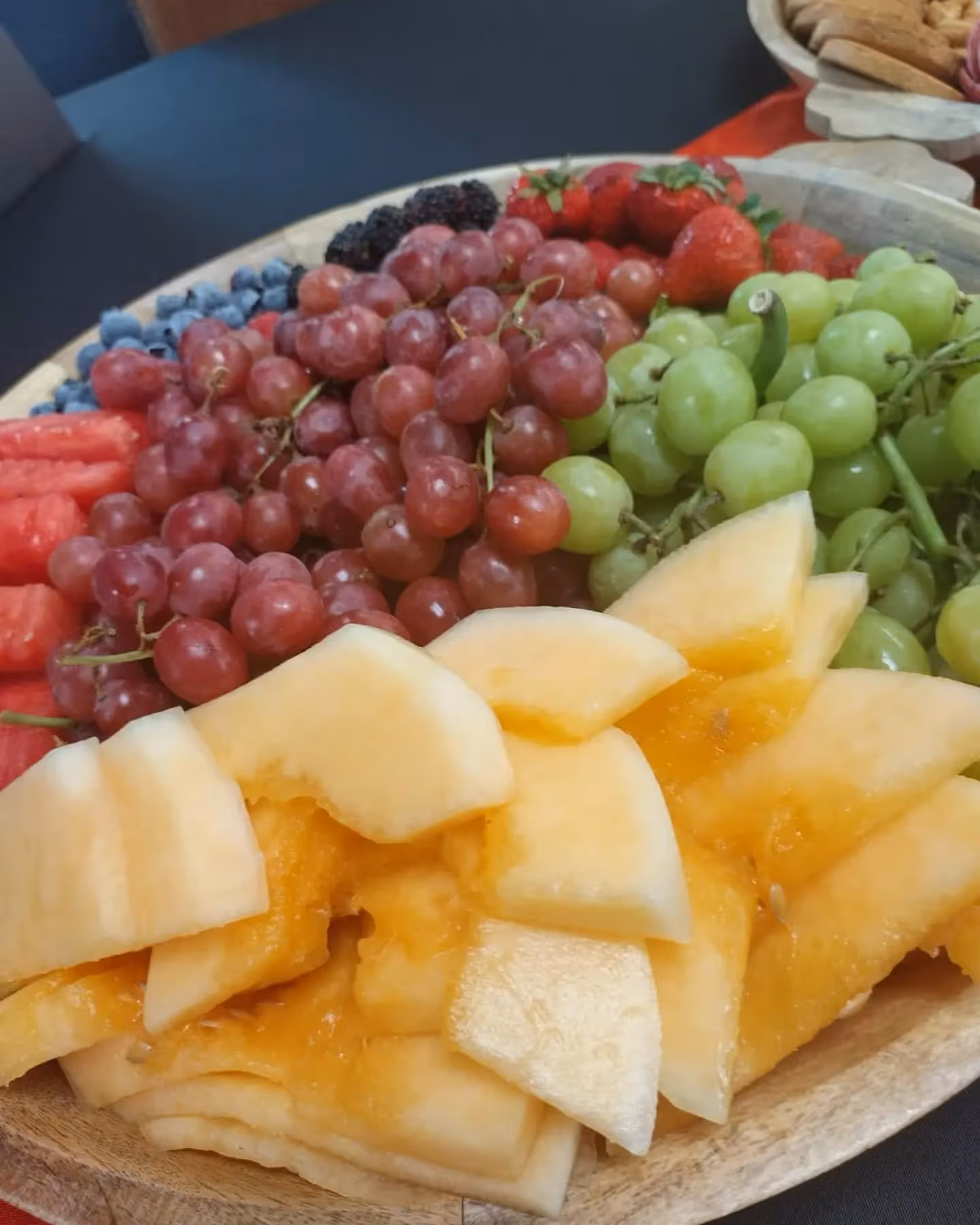 A wooden platter with a variety of fruits on it.