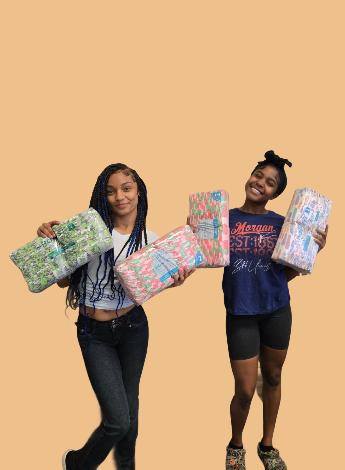 Two smiling young women holding colorful packs of diapers in front of a peach-colored background, showing excitement while supporting a community baby supply initiative.
