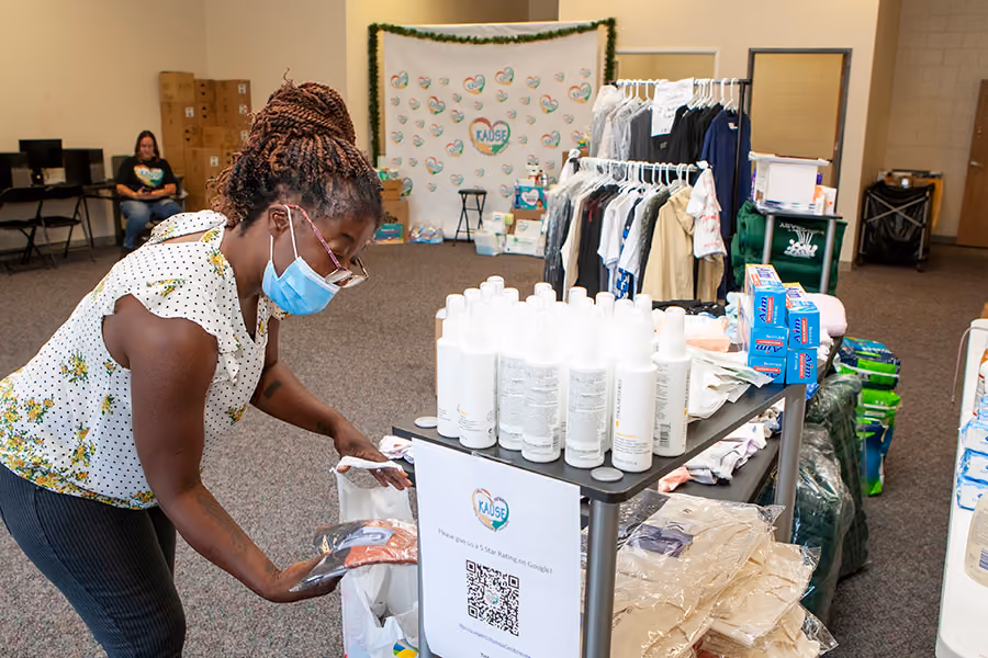 Woman wearing a face mask organizes donated hygiene products and clothes at a community giveaway event inside a KAUSE center.