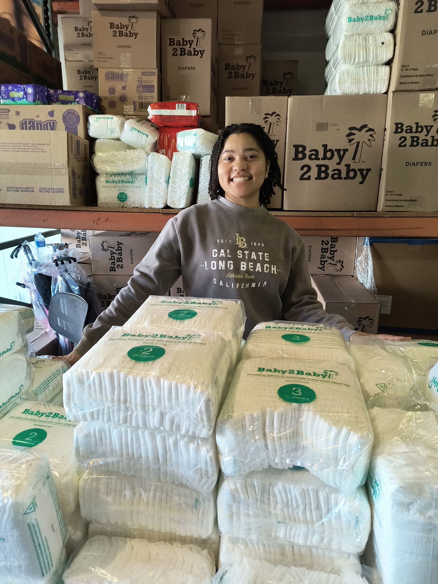 A volunteer with KAUSE stands among donated supplies for babies