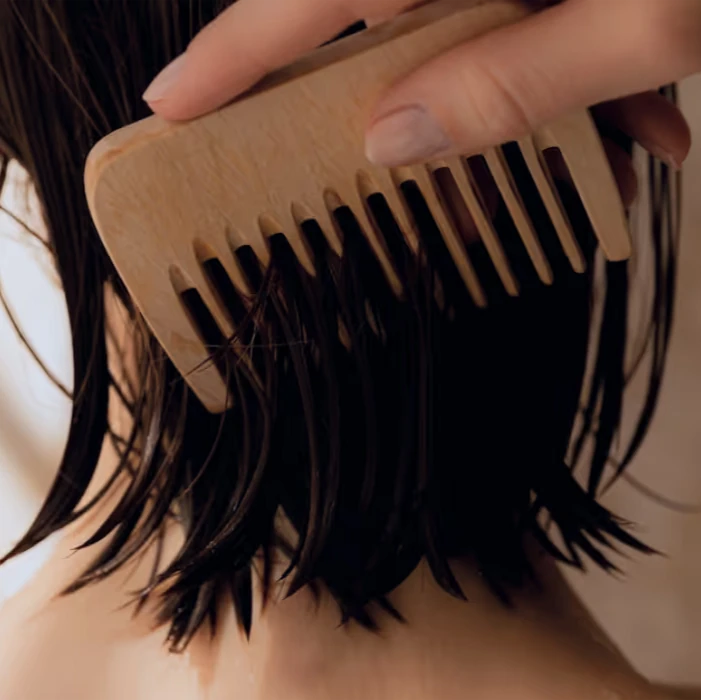 Pente de madeira desembaraçando cabelo escuro