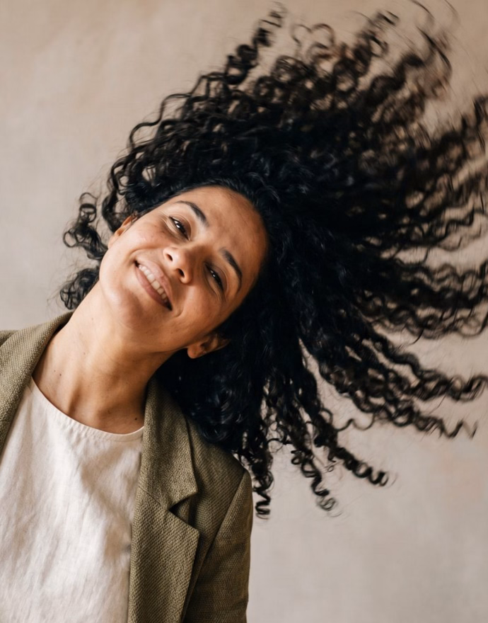 Mulher sorridente balançando o cabelo cacheado