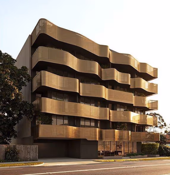 Modern building with five floors featuring wavy, golden-colored balconies illuminated by sunlight.
