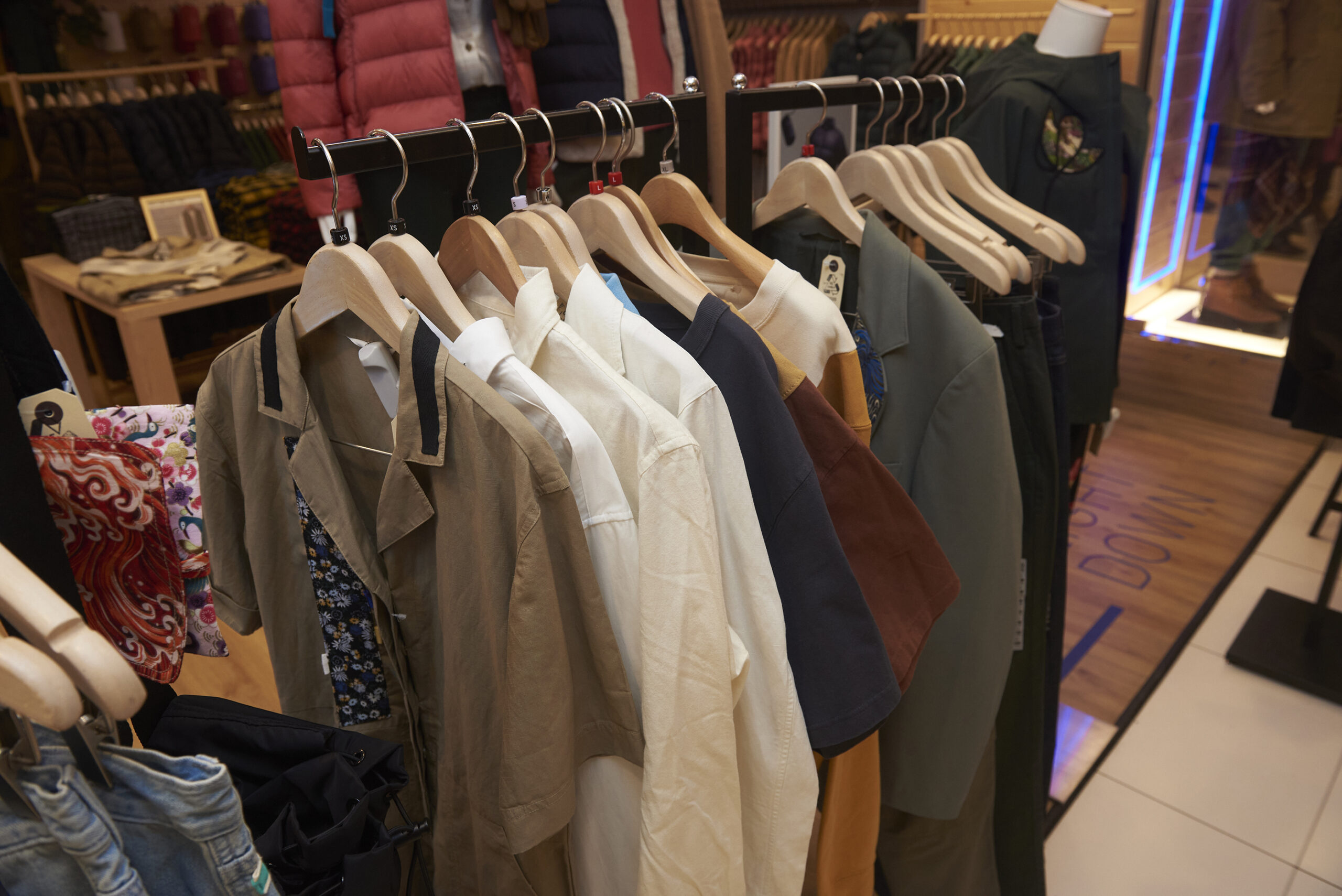 Garments from the RE.LIVE collection hang in a row on a clothing rack in the UNIQLO store.