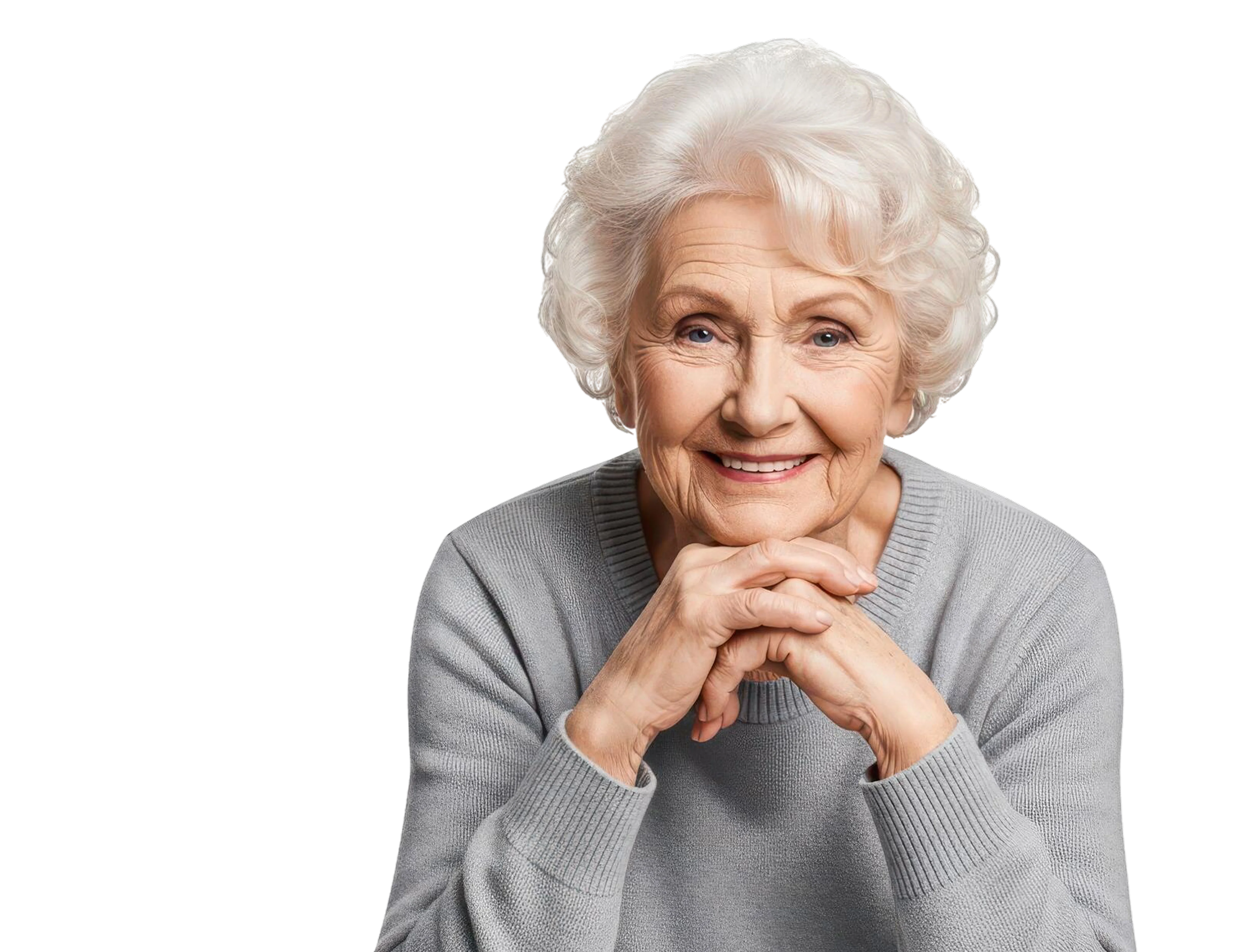 Smiling elderly woman with white curly hair wearing a light gray sweater, resting her chin on her folded hands.