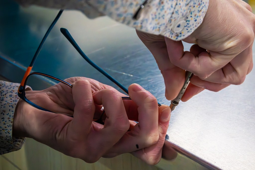 Opticien ajustant la branche d'une paire de lunettes à l'atelier de Martin Opticiens