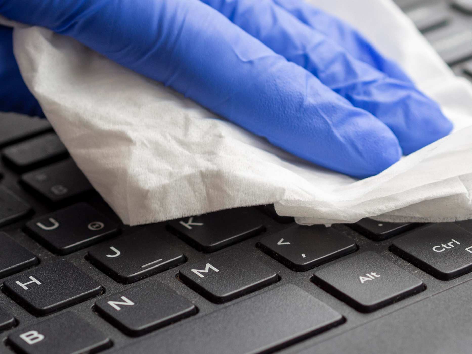 a close up of a keyboard being wiped down with a disinfecting wipe