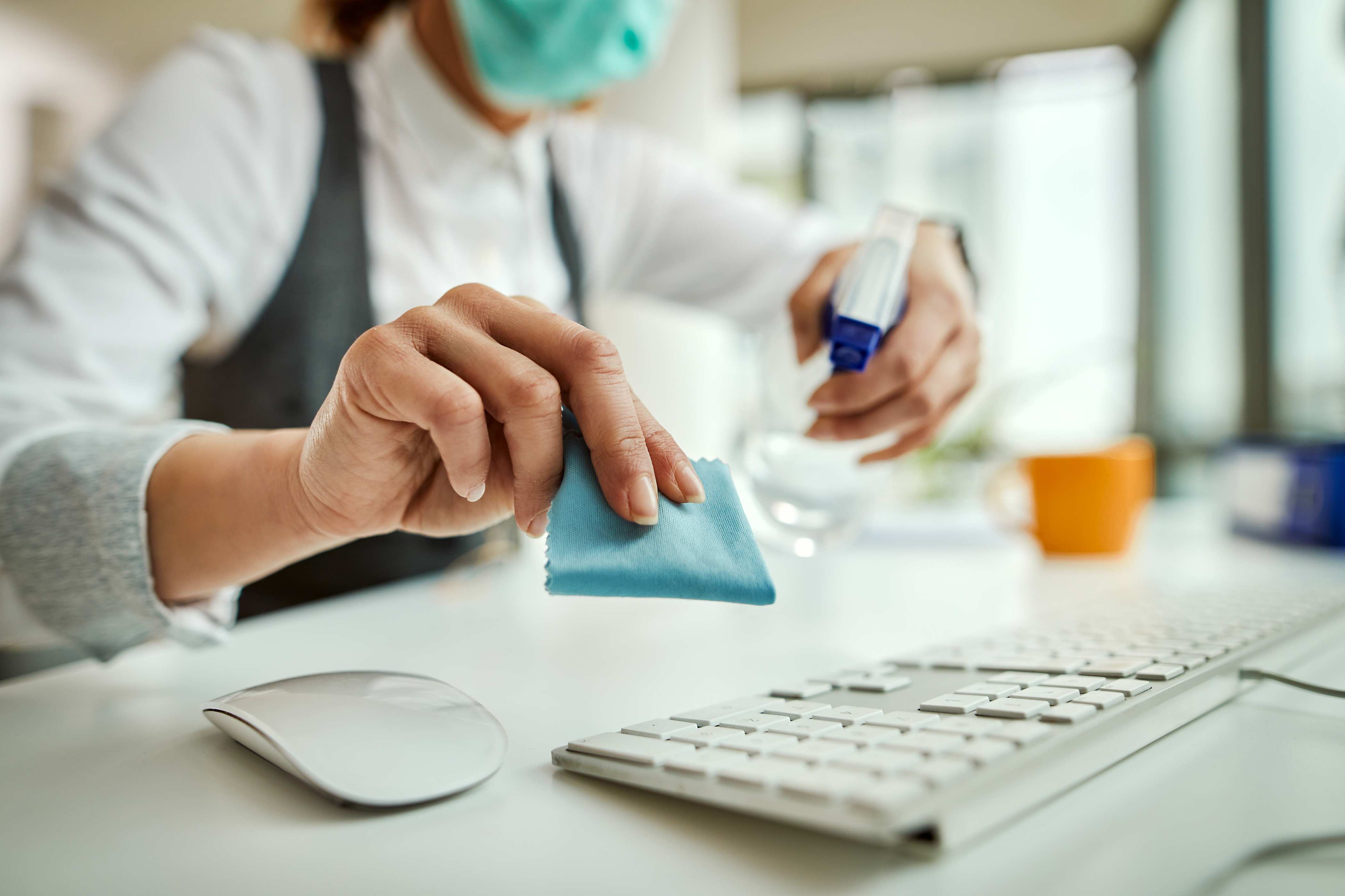 closeup of a businesswoman disinfecting computer keyboard-office