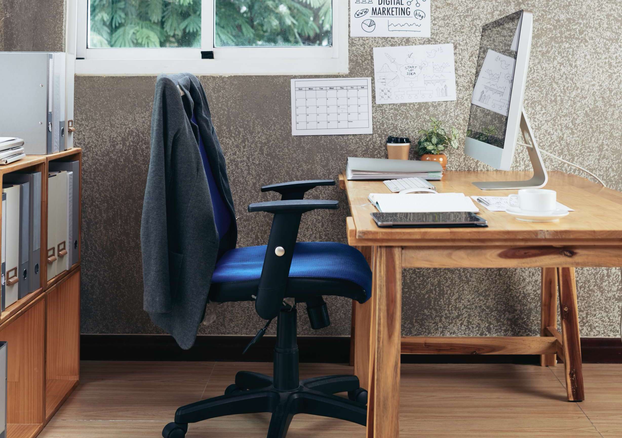 singular desk and chair with suit jacket on it inside an empty office room