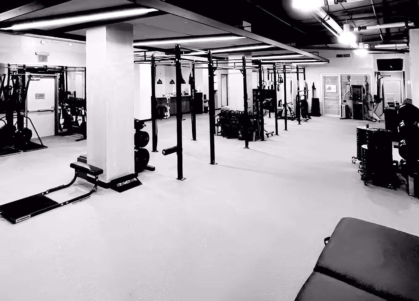 Wide-angle view of a modern gym with workout equipment and mirrors.