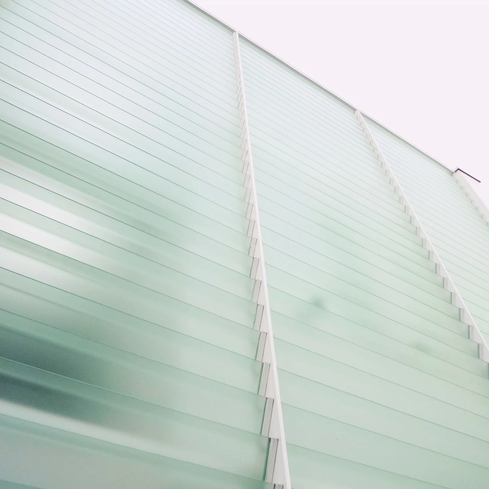 Glass facade with horizontal louvre panels, viewed from below