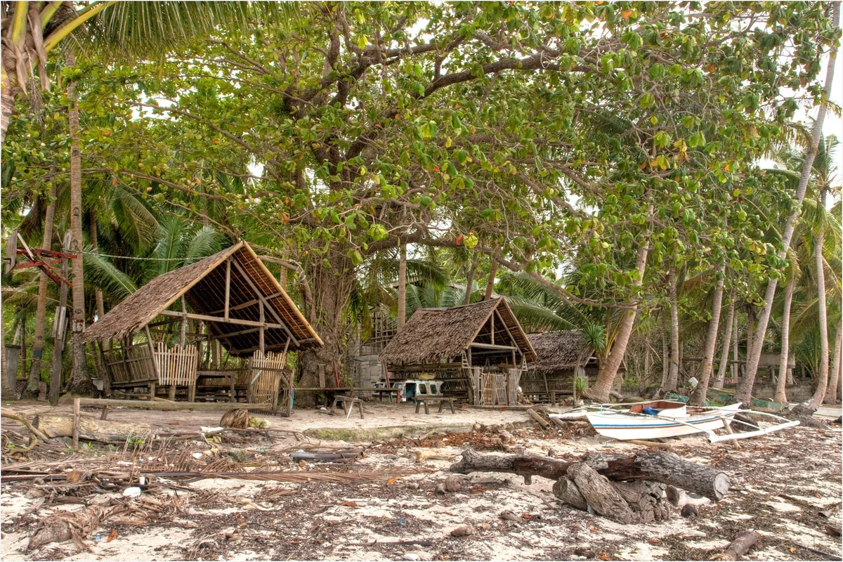 Traditional beach huts and an outrigger boat at Momo Beach in Panglao, Bohol