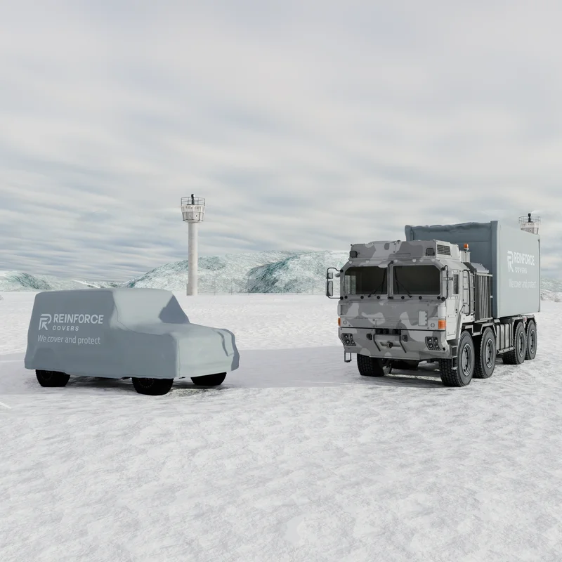Bild in einer schneebedeckten Landschaft. Zu sehen sind ein mit einer Plane verdeckter Geländewagen und ein mit Schneecamouflage bedruckter Militärlkw.