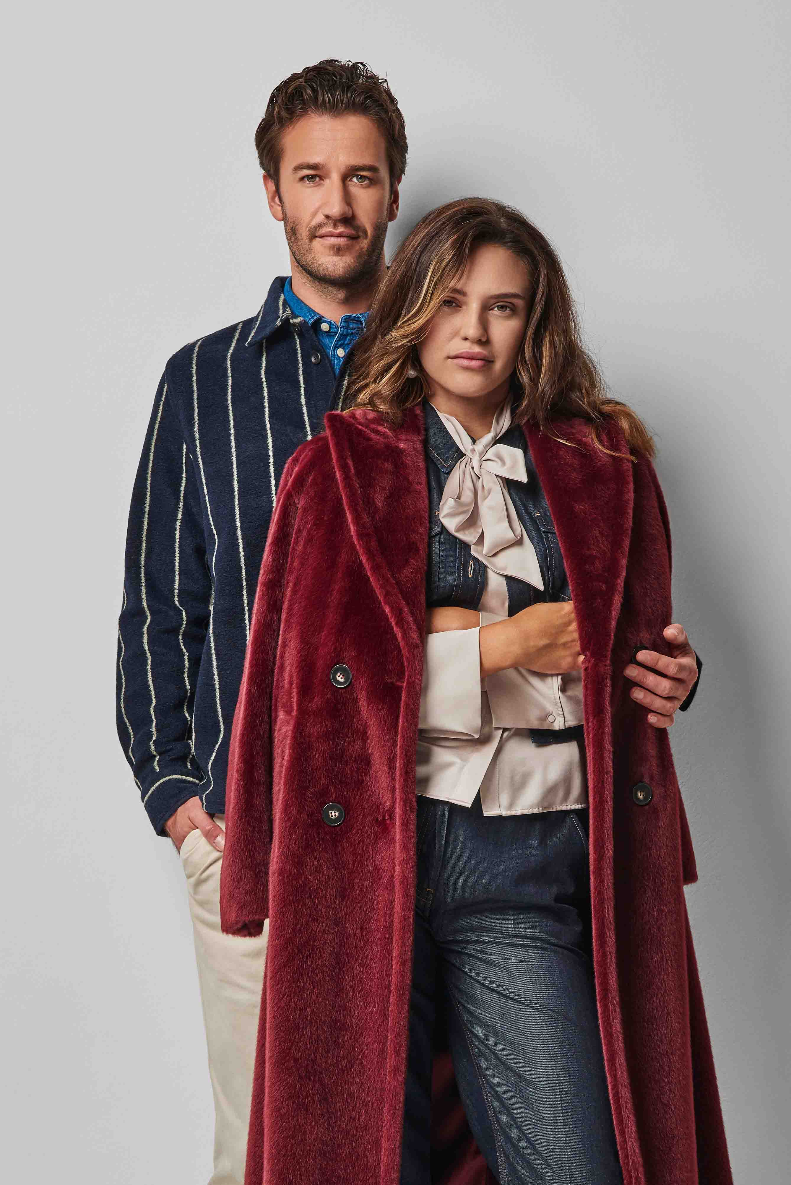 Ein Mann mit gestreifter Jacke steht hinter einer Frau mit rotem Mantel