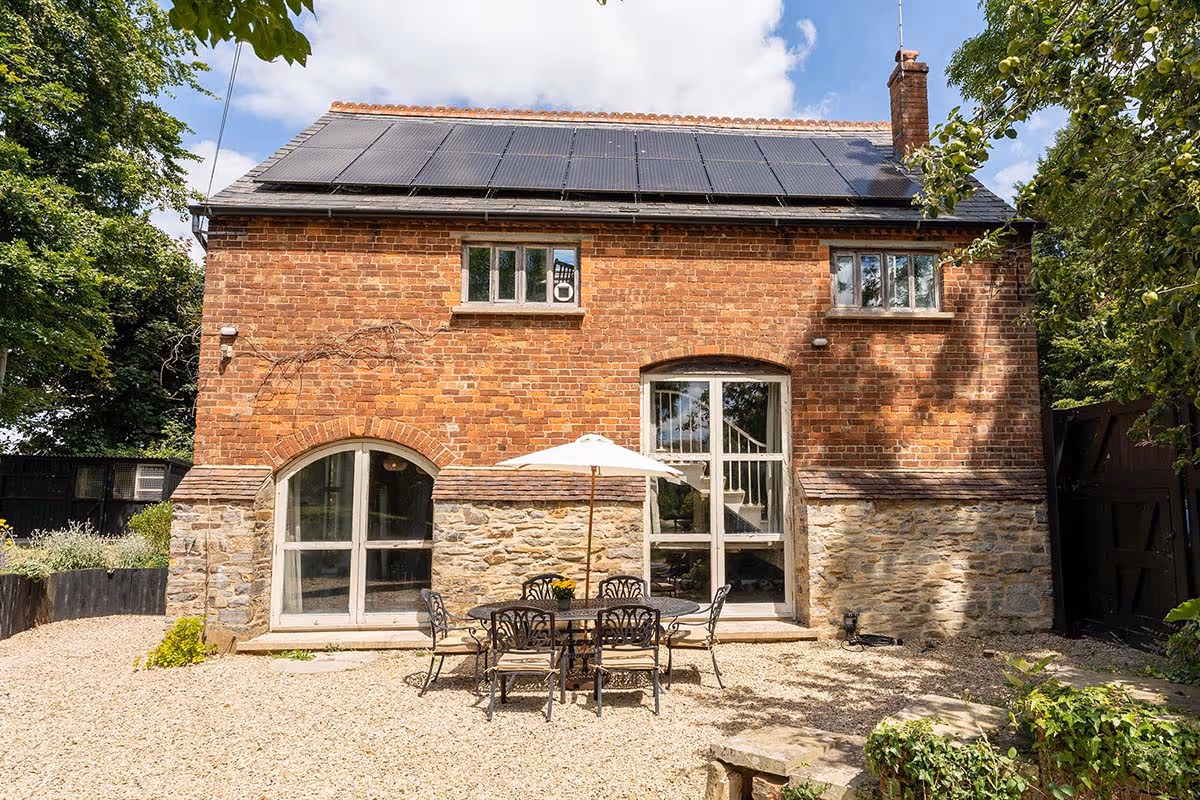 Brick house with solar panels, stone base, and outdoor patio furniture