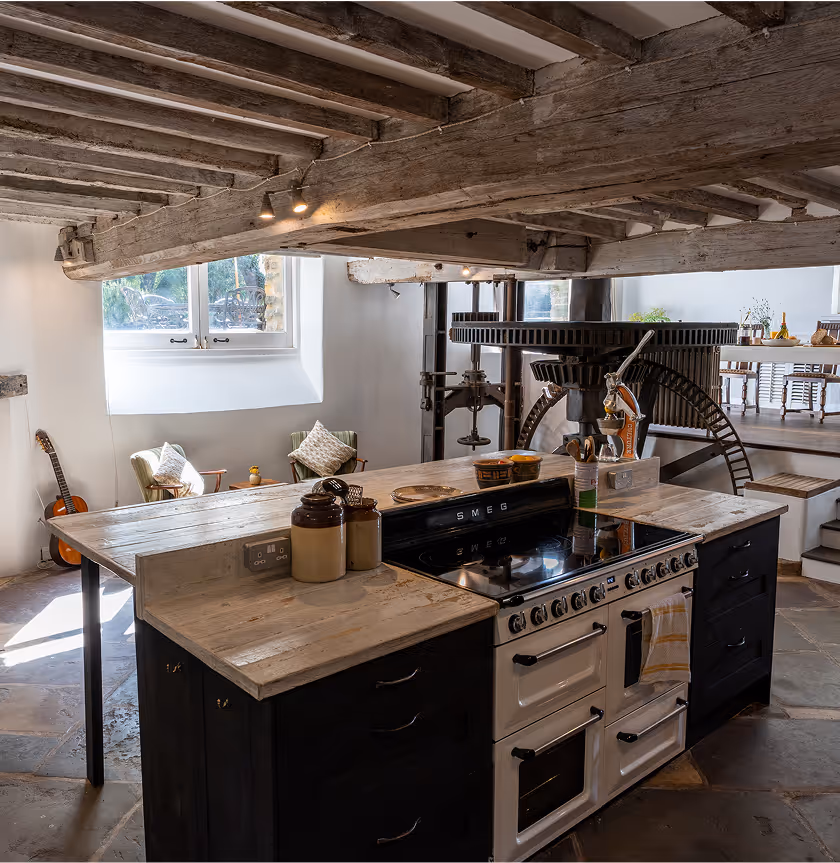 Rustic kitchen with wooden beams, vintage stove, and guitar near window