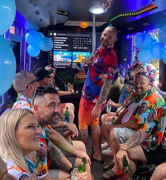 Group of people wearing colorful shirts celebrating inside a Happytrackers bali party bus