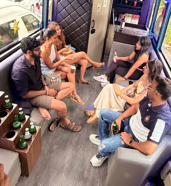 Group of six young adults sitting and chatting inside a modern vehicle lounge with drinks in hand in Bali
