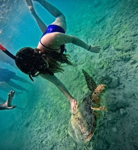 Three women kneeling on a bed wearing robes with 'Bride' and 'Bridesmaid' text, raising their arms in celebration.