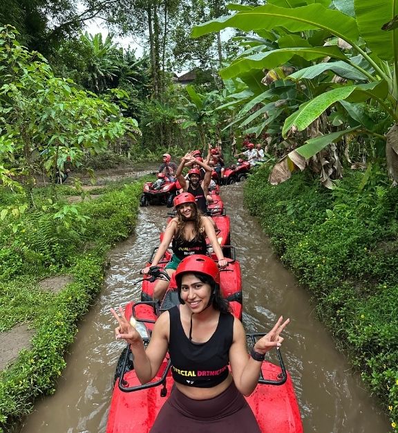 Two young women standing confidently in front of a graffiti wall, wearing black tops and blue jeans.