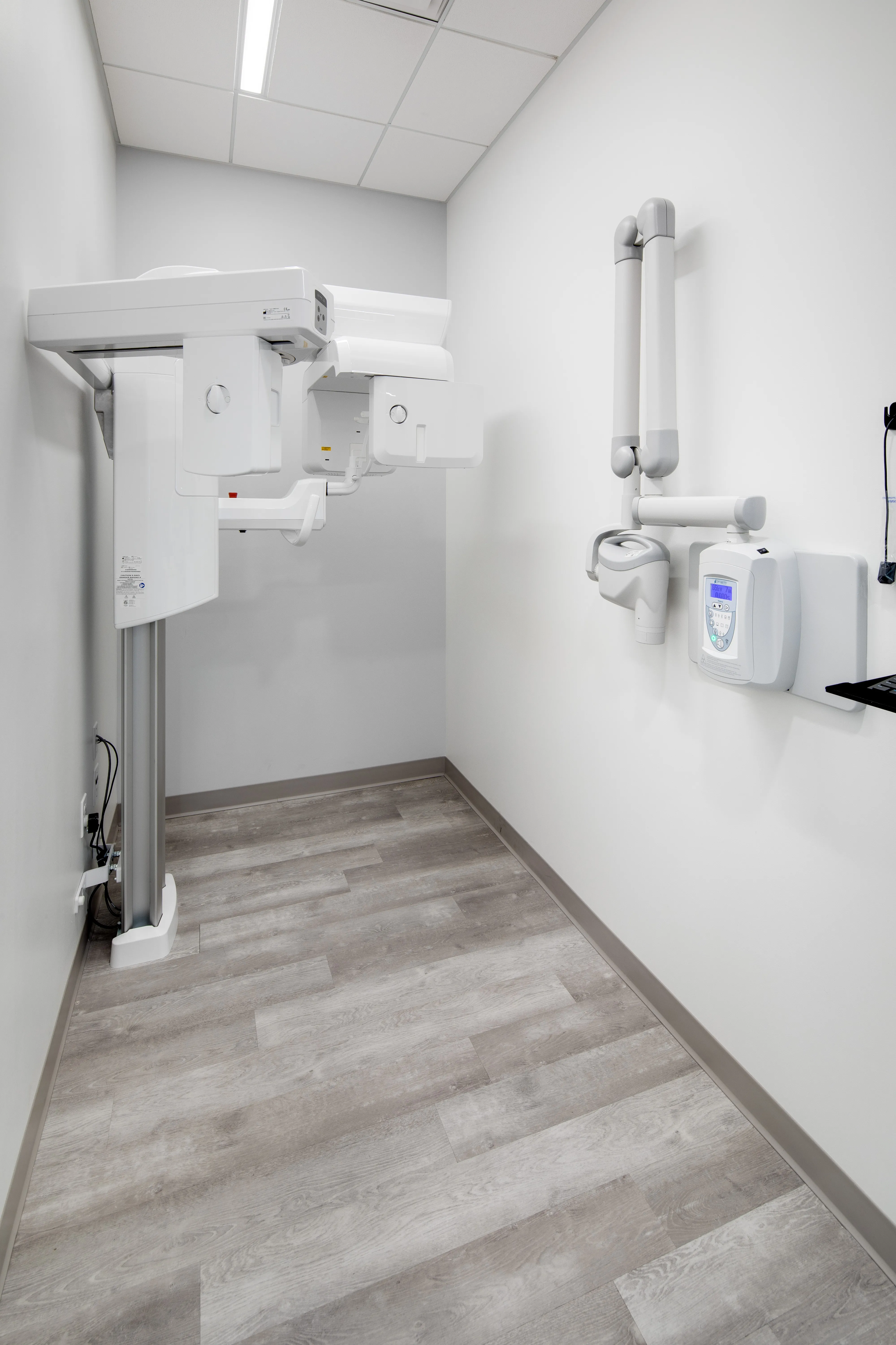 A clean dental X-ray machine installed in a bright room with light wood flooring and white walls at Omnia Dental Care in Chino Hills, CA 