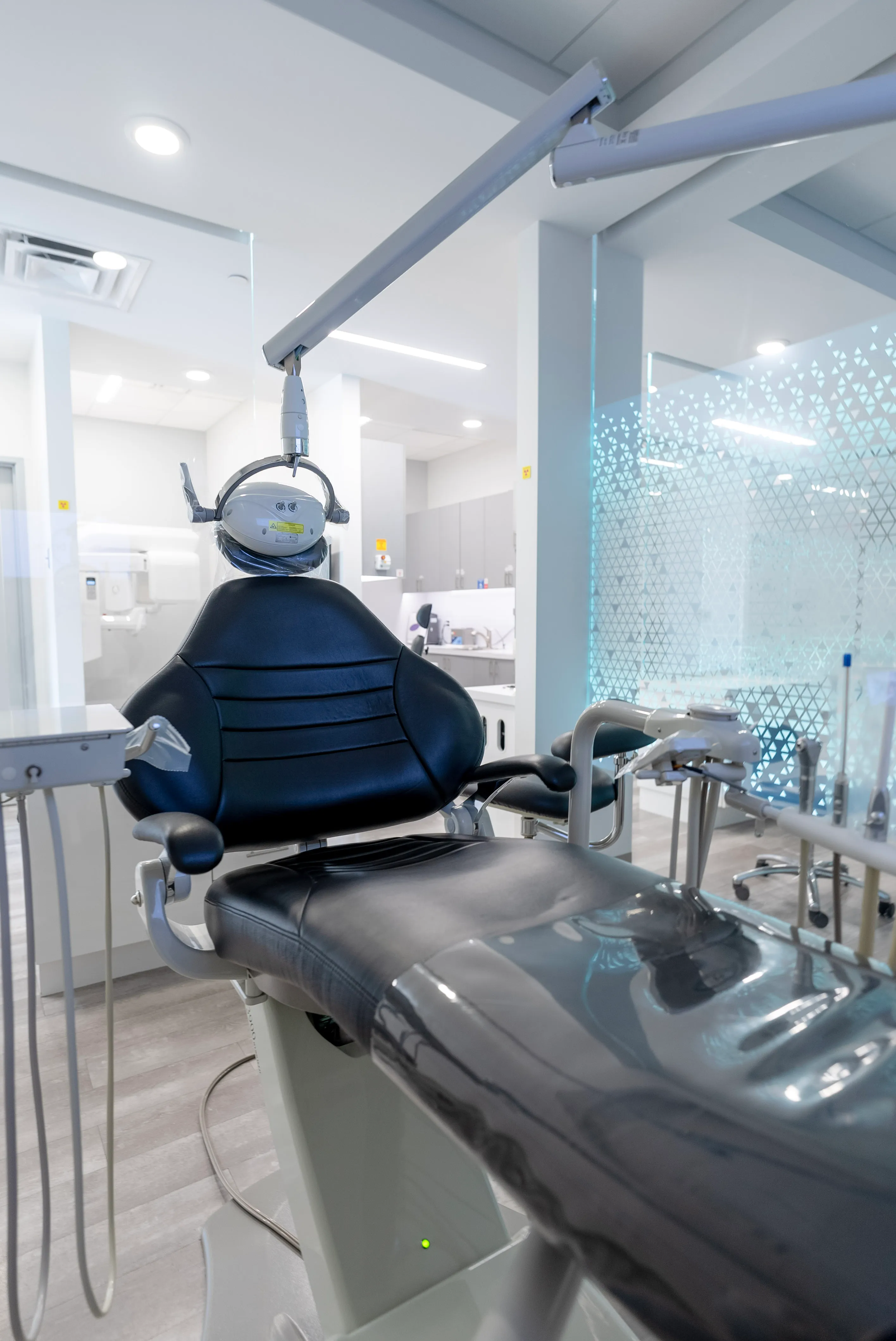 Modern dental chair with attached overhead light and dental instruments in a clean, bright dental clinic at Omnia Dental Care in Chino Hills, CA 