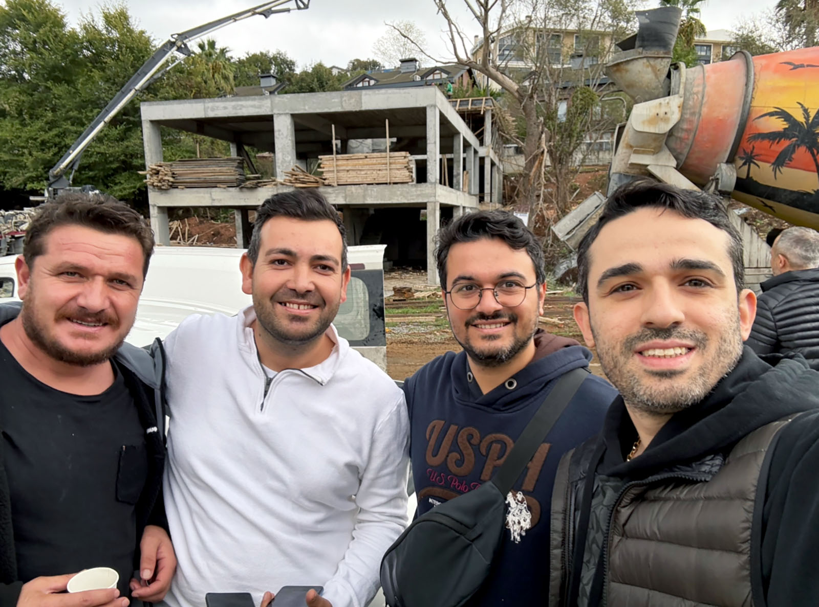 Modern semi-detached houses with large A-frame roofs and expansive glass windows, featuring metal balconies and dark tiled roofing, illuminated by warm evening sunlight.
