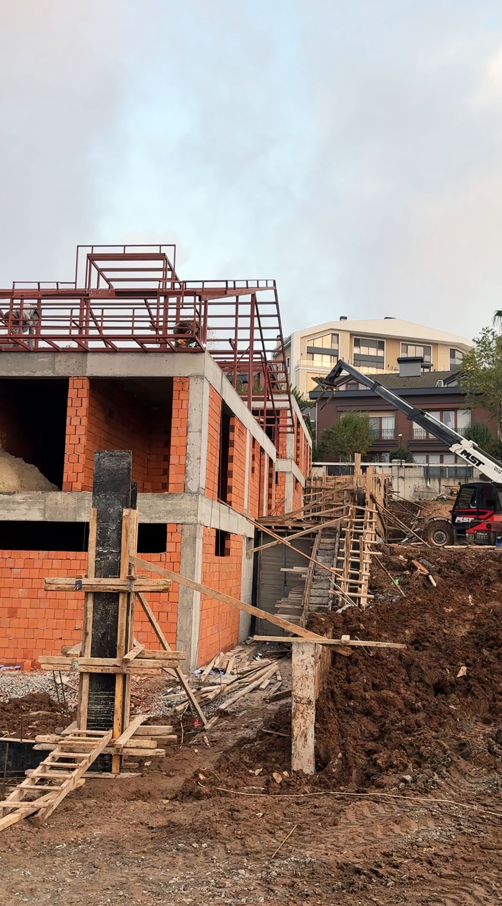 Modern semi-detached houses with large A-frame roofs and expansive glass windows, featuring metal balconies and dark tiled roofing, illuminated by warm evening sunlight.