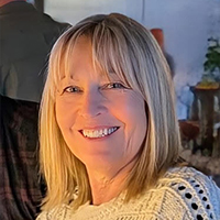 Sandra Starling smiling with blonde hair wearing a white knit sweater.