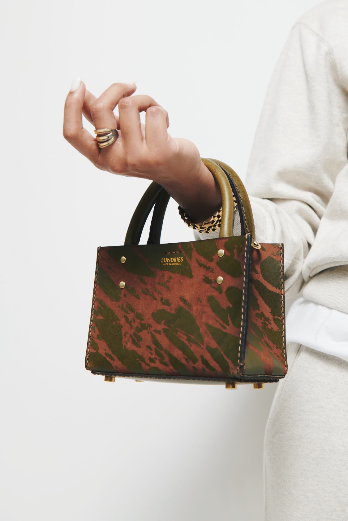 A photo of SUNDRIES marble bag being worn on the wrist. 