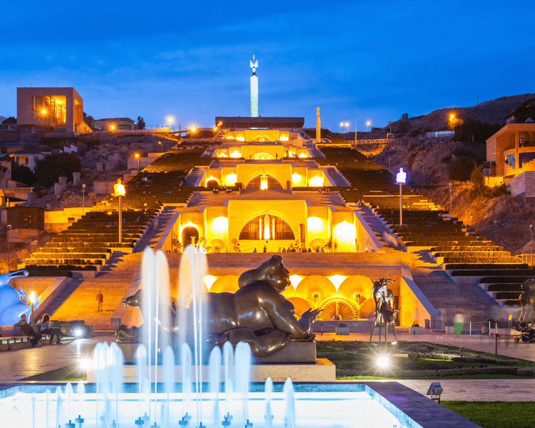 The Cascade Complex in Yerevan, Armenia, lit up at night with fountains, sculptures, and city lights.