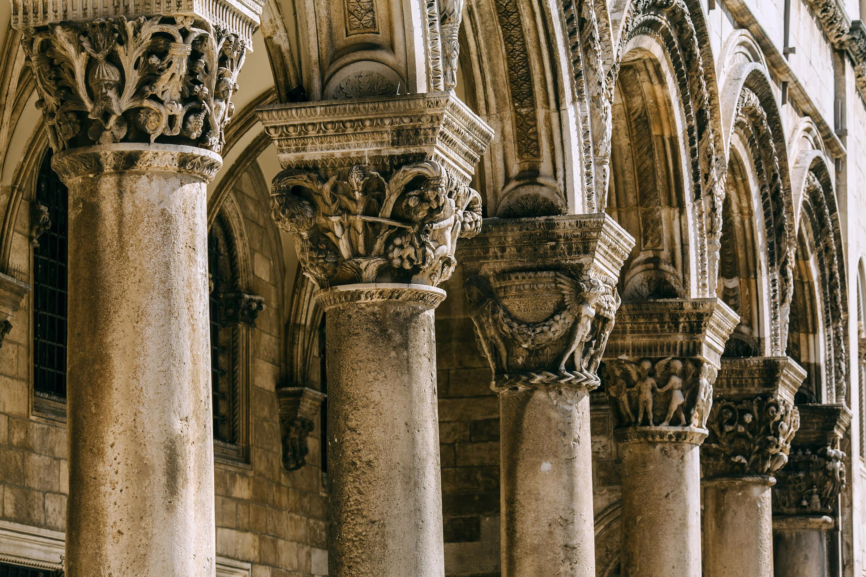 Ornate carved stone columns in a historic building in Dubrovnik, Croatia, showcasing intricate medieval detailing.