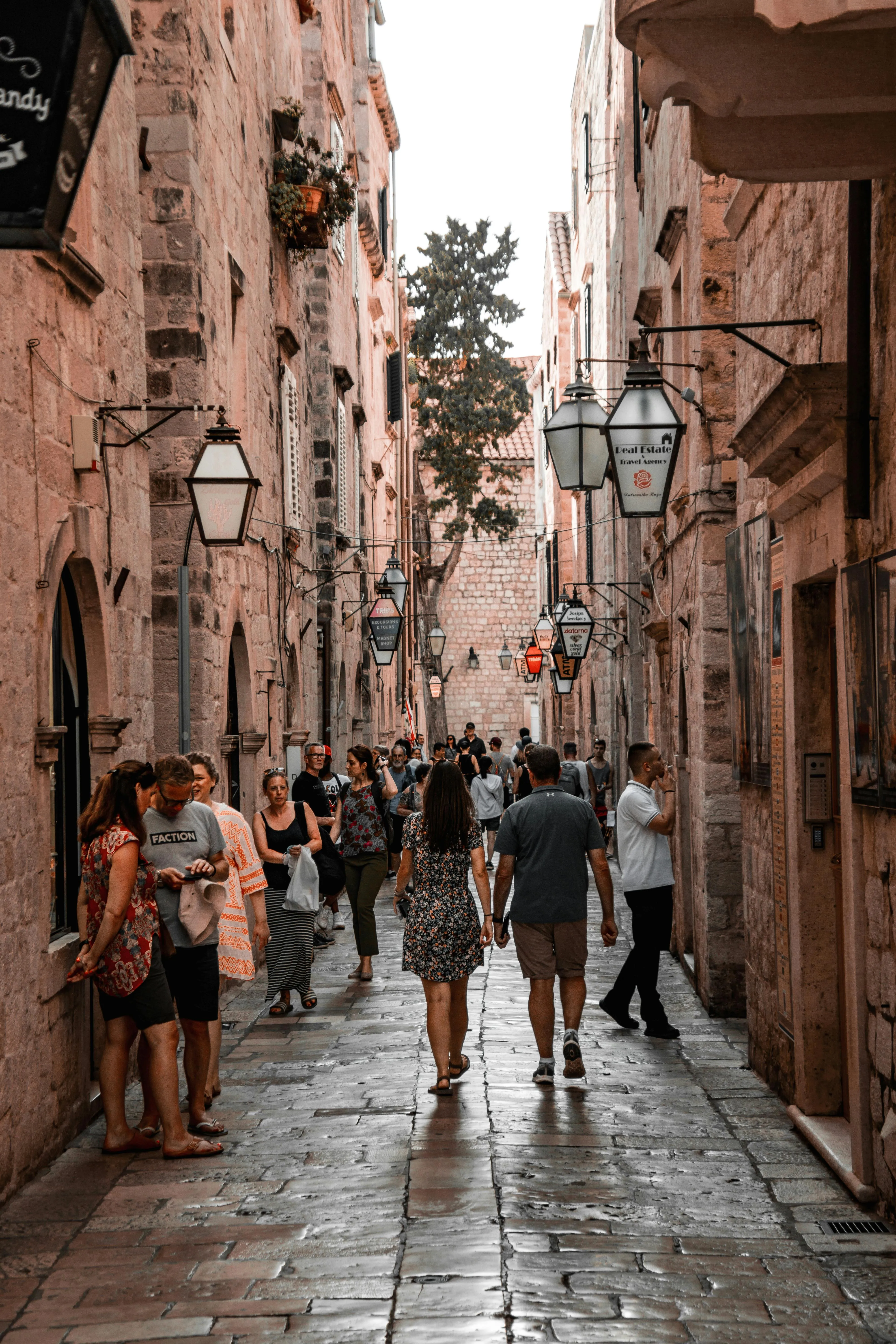 A lively stone-paved street in Dubrovnik Old Town, Croatia, filled with tourists and hanging lanterns.